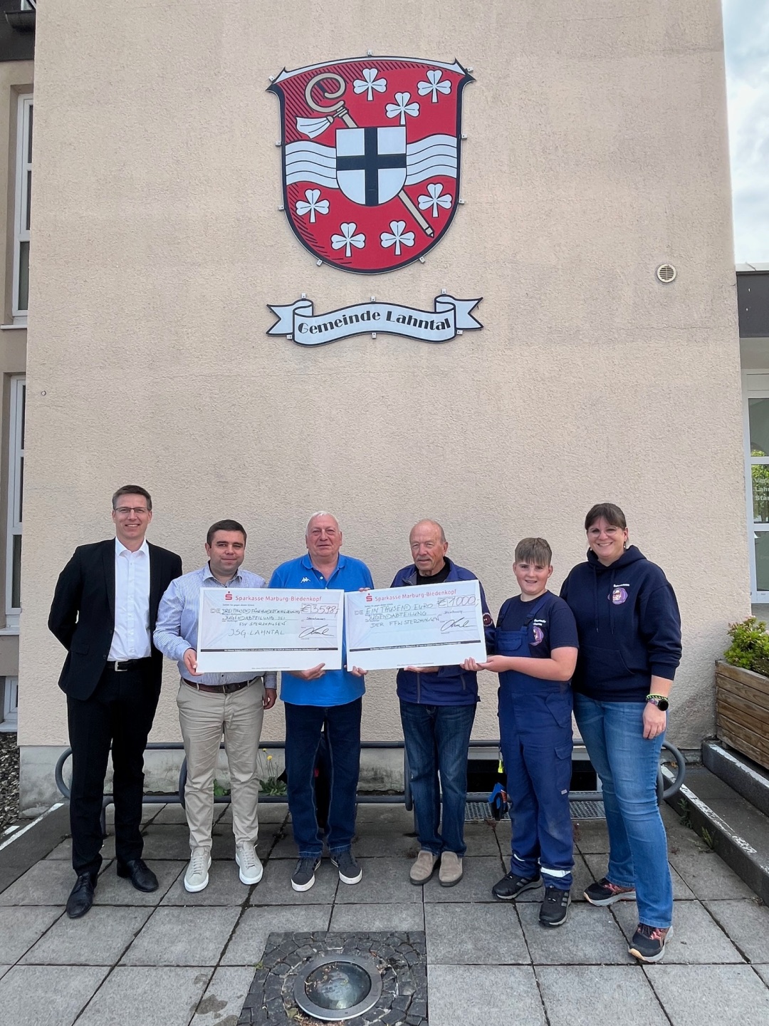 Kaninchenzuchtverein spendet 4.598€ Checkübergabe mit Menschen vor der Gemeinde