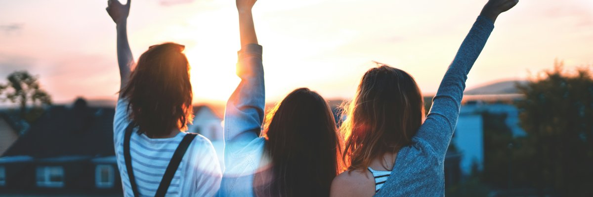Drei Mädchen schauen in den Sonnenuntergang